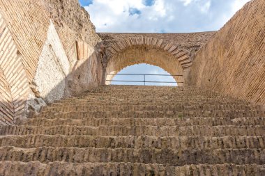 Roma, İtalya - 23 Haziran 2018: Roma forumunun kalıntıları, Flavian Amfitiyatrosu olarak da bilinen Roma Kolezyumu 'nun (Kolezyum, Kolezyum) girişindeki geçitin kapısından görülüyor. Ünlü dünya simgesi. Manzaralı şehir manzarası.