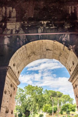 Roma, İtalya - 23 Haziran 2018: Roma forumunun kalıntıları, Flavian Amfitiyatrosu olarak da bilinen Roma Kolezyumu 'nun (Kolezyum, Kolezyum) girişindeki geçitin kapısından görülüyor. Ünlü dünya simgesi. Manzaralı şehir manzarası.