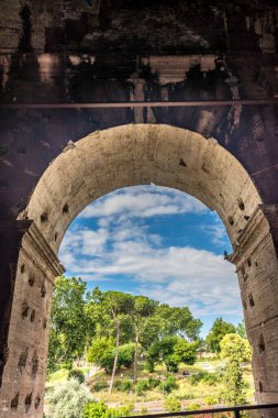 Roma, İtalya - 23 Haziran 2018: Roma forumunun kalıntıları, Flavian Amfitiyatrosu olarak da bilinen Roma Kolezyumu 'nun (Kolezyum, Kolezyum) girişindeki geçitin kapısından görülüyor. Ünlü dünya simgesi. Manzaralı şehir manzarası.