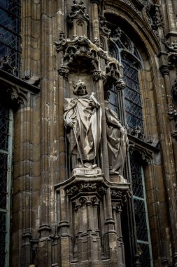 Gent, Belçika, Avrupa 'daki bir binanın duvarında elinde kuş olan bir azizin heykeli.