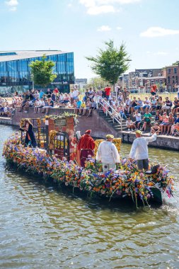 Hollanda, Delft-5 Ağustos 2018: Westland Boat Parade (Varend Corso), şenlikli gösteri, çiçek ve sebzelerle süslenmiş tekneler, Westland bölgesinde renkli yelkenli çiçek geçit töreni