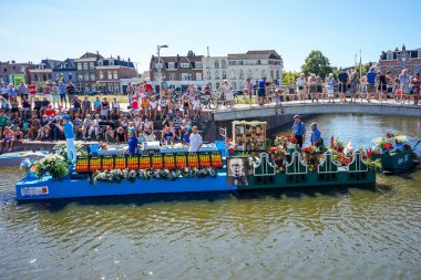 Hollanda, Delft-5 Ağustos 2018: Westland Boat Parade (Varend Corso), şenlikli gösteri, çiçek ve sebzelerle süslenmiş tekneler, Westland bölgesinde renkli yelkenli çiçek geçit töreni