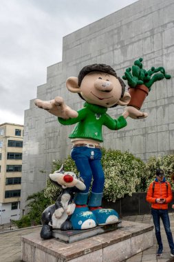 Brüksel, Belçika - Nisan 2017: Parlak bir günde Belçika 'nın Brüksel kentinde bir çizgi film karakteri heykelinin altında bir turist duruyor