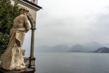 Varenna, İtalya - 31 Mart 2018: Güneşli bir yaz gününde Varenna 'daki güzel Villa Manastırı' na bakan bir heykel. Como Gölü, Lombardy, İtalya