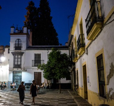 Seville, İspanya - 18 Haziran 2017: Turistler Sevilla 'daki kaldırım taşlı sokaklarda gece, İspanya Haziran 2017