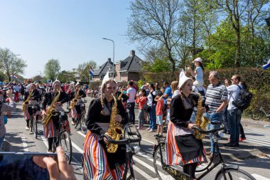 Hollanda, Sassenheim-21 Nisan 2018: Bulbflower Parade 2018, Bloemencorso BollenStreek, şenlikli gösteri, çiçeklerle süslenmiş araçlar, baharın yüzü, Ulusal Hollanda çiçek geçidi, bisikletli saksafon