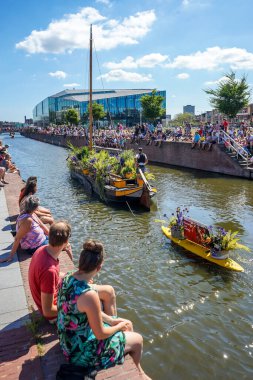 Hollanda, Delft-5 Ağustos 2018: Westland Boat Parade (Varend Corso), şenlikli gösteri, çiçek ve sebzelerle süslenmiş tekneler, Westland bölgesinde renkli yelkenli çiçek geçit töreni