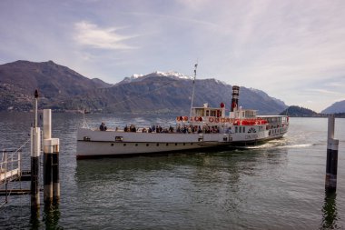 Menaggio, İtalya-2 Nisan 2018: Concordia feribotu göl kenarında arka planda dağ olan insanları taşıyor