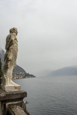 Varenna, İtalya - 31 Mart 2018: Güneşli bir yaz gününde Varenna 'daki güzel Villa Manastırı' na bakan bir heykel. Como Gölü, Lombardy, İtalya