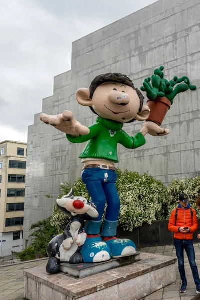 Brüksel, Belçika - Nisan 2017: Parlak bir günde Belçika 'nın Brüksel kentinde bir çizgi film karakteri heykelinin altında bir turist duruyor