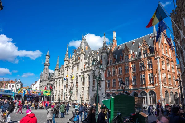 Brügge, Belgien - 17. April: Touristen spazieren an einem strahlend sonnigen Tag mit blauem Himmel auf dem Grote Markt vor dem alten Rathaus in Brügge, Belgien — Stockbild Brügge Belgien April Touristen Spazieren Einem Strahlend Sonnigen Tag Mit — Stockfoto