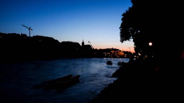 İsviçre, Basel, Ren Nehri Avrupa 'nın arka planında Munster Kilisesi ile birlikte şehir binalarının önünden geçiyor.