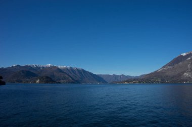 Avrupa, İtalya, Menaggio, Como Gölü. Arkasında dağ olan büyük bir su kütlesi.