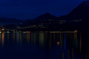 Avrupa, İtalya, Varenna, Como Gölü, büyük bir su kütlesi ve karanlıkta bir dağ.