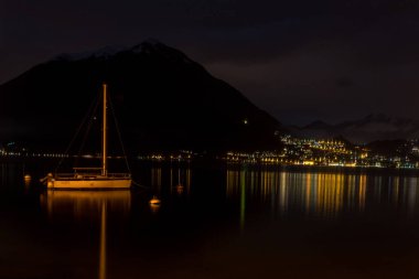 Avrupa, İtalya, Varenna, Como Gölü, karanlıkta teknesi olan büyük bir su kütlesi.