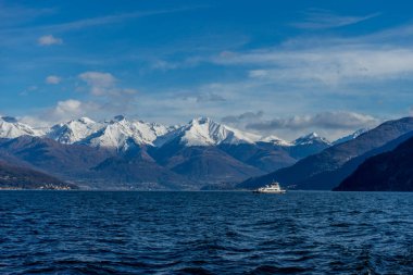 İtalya, Bellagio, Como Gölü 'nde karla kaplı arka planı olan bir tekne.