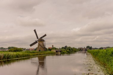 Hollanda, Rotterdam, Kinderdijk, bir kanal boyunca yemyeşil çimenlerin üzerindeki miras yel değirmeni