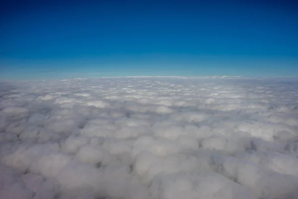 Clouds in the sky viewed from a plane against a blue sky against the horizon