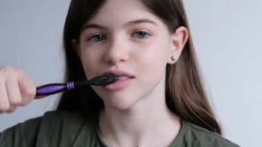 Küçük güzel kız dişlerini diş fırçası ve diş macunuyla fırçalıyor.