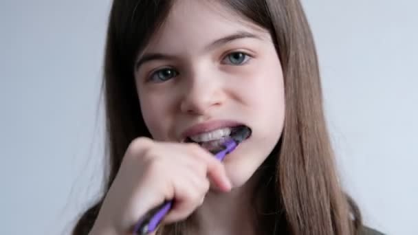 Pequeña chica hermosa se cepilla los dientes con un cepillo de dientes y pasta de dientes — Vídeos de Stock