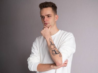 Kolunda yılan dövmesi olan yakışıklı bir genç.