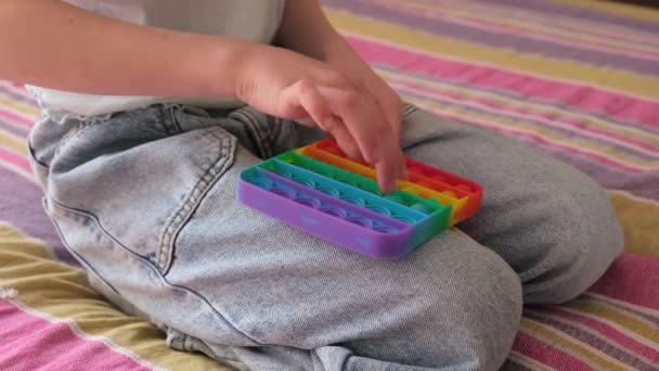 Детские руки нажимают на игрушечные фиксаторы антистресса Pop It — стоковое видео