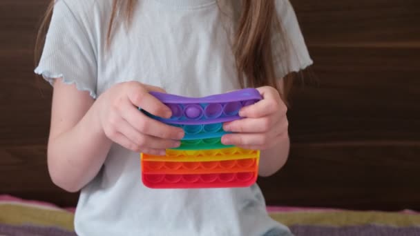 Malá holka si hraje se silikonovou hračkou antistress pop it, popit — Stock video
