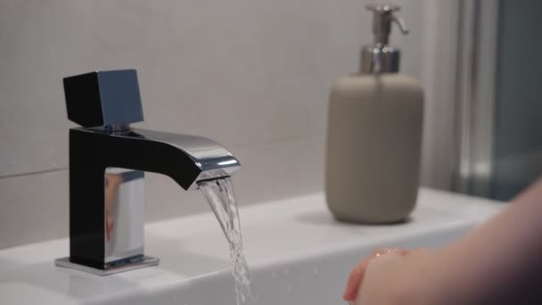 Het kind wast zijn handen onder stromend water — Stockvideo