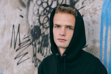 Kapüşonlu, üzgün, yakışıklı bir gencin portresi.