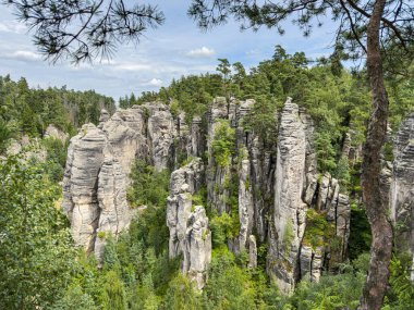 Çek Cumhuriyeti 'nin Bohemya Cenneti' nde (Cesky Raj) ünlü bir kum taşı oluşumu olan Prachov Kayaları 'nın manzaralı yaz fotoğrafı. Manzarada uzun kumtaşı kuleler, orman vadileri ve yürüyüşçüler arasında popüler dar yollar ve fotoğraflar yer almaktadır.