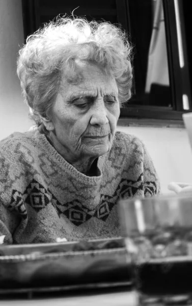 Black and white contrast portrait of an elderly woman on dinner