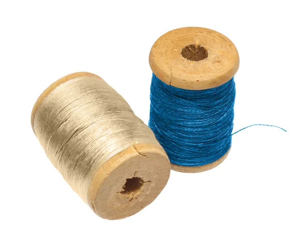 Due thread di bobina di legno dai fili beige su uno sfondo bianco e il blu — Foto Stock