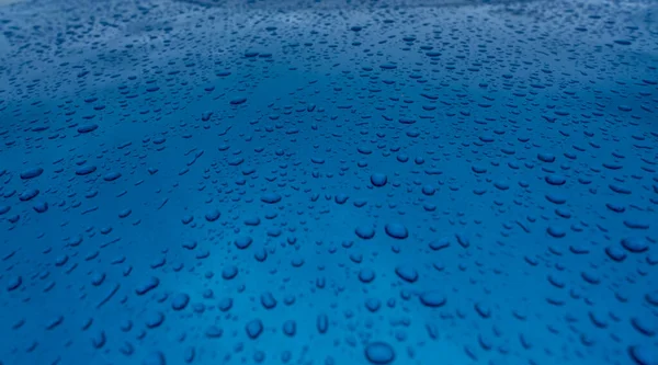 自然パターンできれいな青のテクスチャに水滴スプラッシュ 車のフードの青い表面に雨が降ります 青い背景に水滴 閉じる青い車の雨のドロップアップ 爽やかでアクアのコンセプト — ストック写真