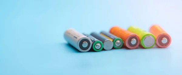 Rechargeable battery on blue background. Selective focus negative terminals of rechargeable lithium-ion batteries. AA and AAA size of old Li-ion battery. Battery recycling concept. Green power energy.