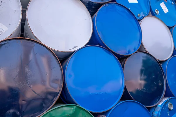 Old chemical barrels. Blue, white, and green oil drum. Steel oil tank. Toxic waste warehouse. Hazard chemical barrel. Industrial waste in old drum. Hazard waste storage in factory. Metal barrels.
