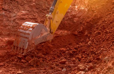 İnşaat alanında toprak kazarak çalışan bir kepçe. Bir kova kazma toprağı. Sürüngen kazıcı toprağı eşeliyor. Yakın plan kepçe kova dolusu sarı kepçe. Dünyayı yerinden oynatıyor. Hendek makinesi.