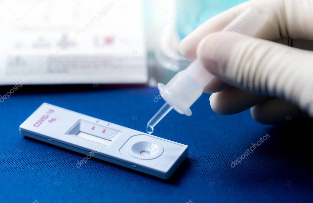 Hand holding sample tube and drops in the test device of covid 19 antigen self test. Antigen test kit for detection of coronavirus infection. Rapid antigen test. Coronavirus diagnosis. Medical device.