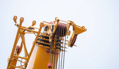 Çelik kablolar ve makara ile vinç kaldırma sistemi. Altyapı geliştirme, mühendislik hassasiyeti, güvenlik operasyonları ve modern endüstriyel teknoloji için ağır inşaat makineleri.