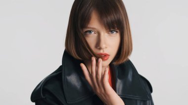 Kısa saçlı ve kırmızı dudaklı güzel manken beyaz arka planda kameraya şehvetle poz veriyor.