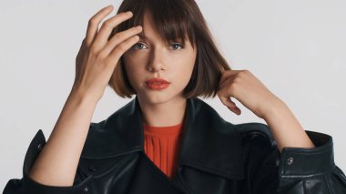 Kırmızı dudaklı çekici esmer kız saçlarını tarıyor beyaz arka planda kendine güveni tam görünüyor.