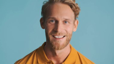 Mavi arka planda heyecanlı görünen genç sarışın sakallı adamın portresi.