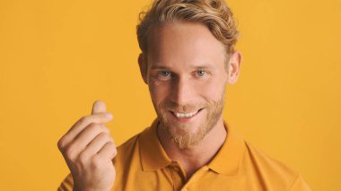 Çekici, neşeli, sarışın, sakallı adam renkli arka planda para hareketi gösteriyor.