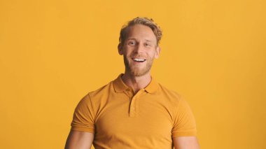 Genç yakışıklı, sarışın, sakallı adam renkli arka planda mutlu görünüyor. Pozitif ifade