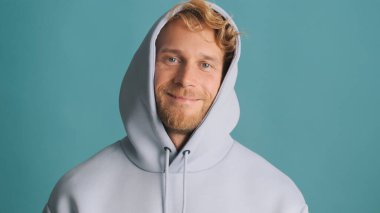 Yakışıklı, şık, sarışın, sakallı adam mavi arka planda gülümsüyor. Çekici, sıradan bir adam.