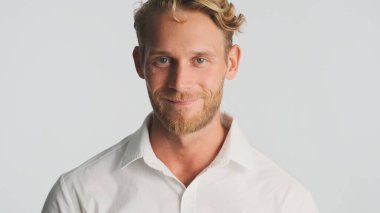 Çekici sarışın sakallı adam beyaz arka planda mutlu görünüyor. Yüz ifadesi