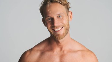 Yakışıklı, sarışın, sakallı, mutlu görünen beyaz arka planda izole edilmiş kamerada gülümseyen adam. Stüdyoda poz veren erkek model.