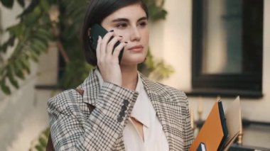 Modern, güzel iş kadını akıllı telefondan konuşuyor. Şehir caddesinde taksi bekliyor. Zarif bayan işe gidiyor.
