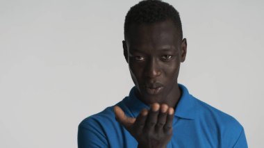 Beyaz arka plan üzerinden kız arkadaşına hava öpücüğü gönderen kendinden emin Afro-Amerikalı adamın portresi. Aşk ifadesi