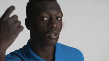 Genç Afrikalı Amerikalı adam beyaz arka plandan kameraya bakıyor. İfade ver.