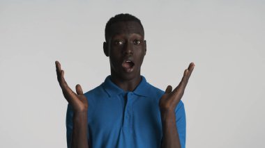 Ağzı açık afro-amerikan bir adam beyaz arka planda izole edilmiş kameraya bakıyor.